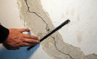 A wall with a large crack is being inspected by a professional in Los Angeles, CA